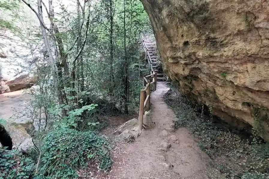 ruta por la hoz de beteta: paso de unas escaleras de madera junto a una roca impresionante